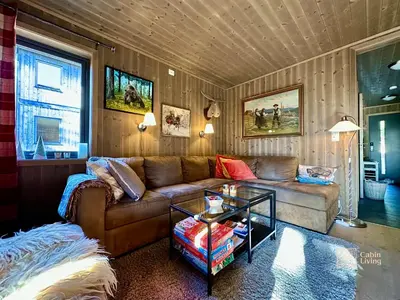 a living room with a couch and a table at Cozy apartment ski in out, BBQ & Wifi Sjusjøen in Sjusjøen