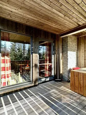 a screened in porch with glass doors on a house at Cozy apartment ski in out, BBQ & Wifi Sjusjøen in Sjusjøen