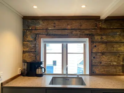 a kitchen with a sink and a wooden wall at Entire renovated apartment from 1780 with Kitchen, Bath, Bedroom, and Living Room in Skuteviken in Bergen