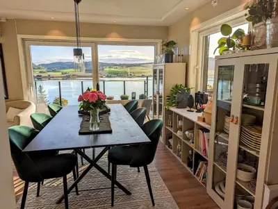 a dining room with a table and chairs and a large window at Nyoppusset hus med utsikt. in Steinkjer