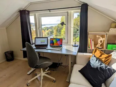 a desk with two laptops on it in a room with a window at Nyoppusset hus med utsikt. in Steinkjer
