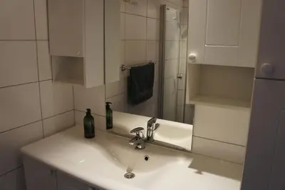 a white bathroom with a sink and a mirror at Hafjell Farmhouse in Øyer