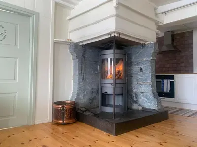a stone fireplace in a living room with a stove at Hafjell Farmhouse in Øyer
