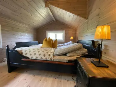 a bedroom with a bed in a wooden cabin at Bjørnebuhytten, Geilo, 13 sengeplasser med privat Jacuzzi og el-bil-lading in Geilo