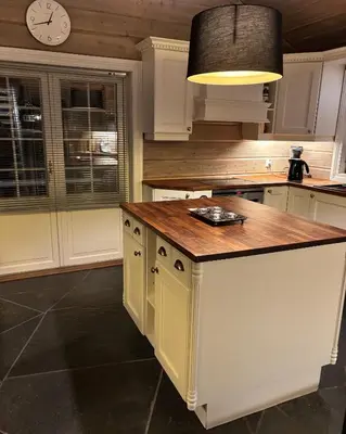 a kitchen with a kitchen island with a clock on the wall at Bjørnebuhytten, Geilo, 13 sengeplasser med privat Jacuzzi og el-bil-lading in Geilo