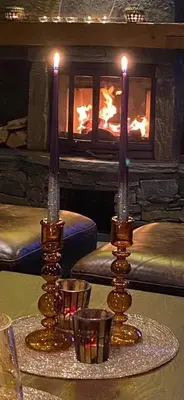 two candles on a table in front of a fireplace at Bjørnebuhytten, Geilo, 13 sengeplasser med privat Jacuzzi og el-bil-lading in Geilo