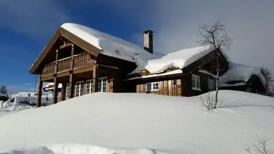 a house covered in snow with a pile of snow at Bjørnebuhytten, Geilo, 13 sengeplasser med privat Jacuzzi og el-bil-lading in Geilo