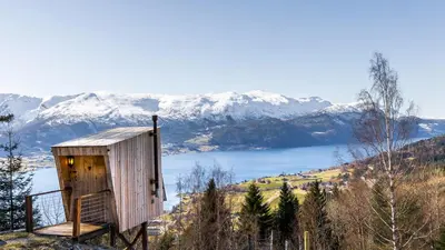 a wooden out house on a hill with snow covered mountains at Engeset Trehytter in Vereide