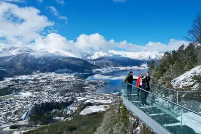 a group of people standing on a viewing platform overlooking a river and mountains at Engeset Trehytter in Vereide
