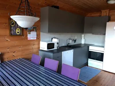 a kitchen with purple chairs and a table with a microwave at Holiday Home Kalavåg by Interhome in Kalavåg