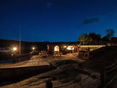 a deck with a picnic table and lights at night at Holiday Home Kalavåg by Interhome in Kalavåg