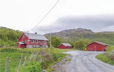 a red house on a dirt road with mountains in the background at Bassebuupdalstøl in Tyinkrysset