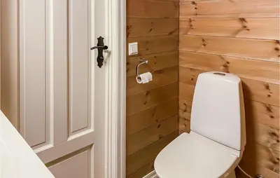 a bathroom with a toilet and a wooden wall at 4 Bedroom Awesome Home In Nordfjordeid in Nordfjordeid