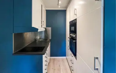 a kitchen with white cabinets and blue walls at 1 Bedroom Amazing Apartment In Øyer in Øyer
