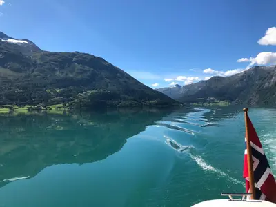 a boat on a river with mountains in the background at Tunold Gård - Olahuset in Oppstryn
