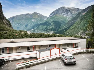 a car parked in a parking lot in front of mountains at Trolltunga Hostel in Tysso