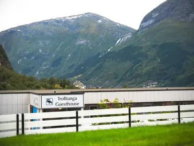 a building with a sign in front of a mountain at Trolltunga Hostel in Tysso