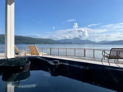 a swimming pool with chairs and a view of the water at Villa Blue Dream in Kristiansund