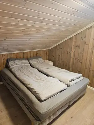 a bed in a room with a wooden ceiling at Hytte i Ringsaker (Ljøsheim/Sjusjøen) in Ringsaker