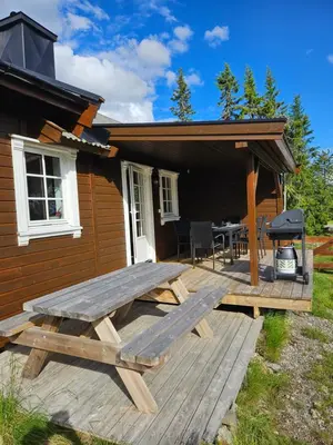a wooden deck with a picnic table in front of a house at Hytte i Ringsaker (Ljøsheim/Sjusjøen) in Ringsaker