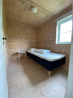 a bed in a wooden room with a window at Hytte i landlige omgivelser på Hadeland in Gran