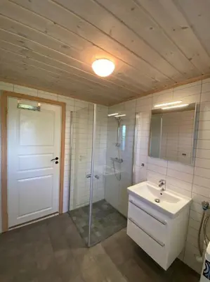 a bathroom with a sink and a shower and a mirror at Hytte i landlige omgivelser på Hadeland in Gran
