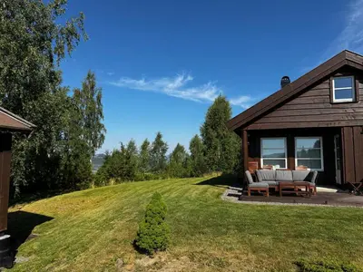 a house on a hill with a couch on a lawn at Hytte i landlige omgivelser på Hadeland in Gran