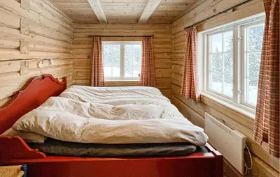 a bed in a log cabin bedroom with two windows at 3 Bedroom Gorgeous Home In Sjusjøen in Sjusjøen