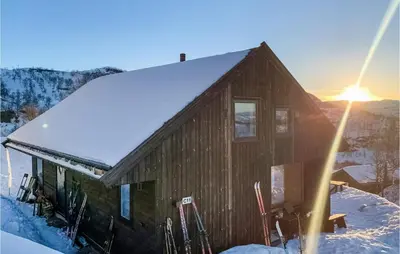a cabin in the snow with the sun setting at Beautiful Home In Jøsenfjorden in Gullingen