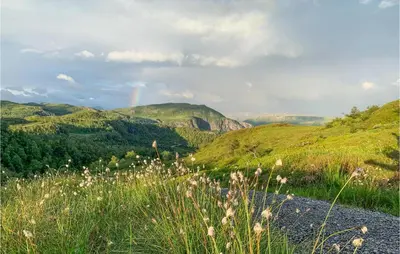 a rainbow in the sky over a green hills at Beautiful Home In Jøsenfjorden in Gullingen
