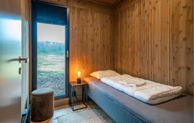 a bed in a wooden room with a window at 3 Bedroom Nice Home In Vøringsfoss in Maurset