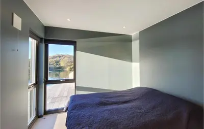 a bedroom with a bed and a large window at 5 Bedroom Lovely Home In Urangsvåg in Ervik