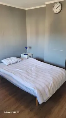 a bedroom with a large bed with a clock on the wall at Comfortable zone in Hønefoss
