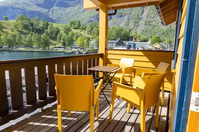 a table and chairs on a balcony with a view of the water at Flåmsbrygga Apartments in Flåm
