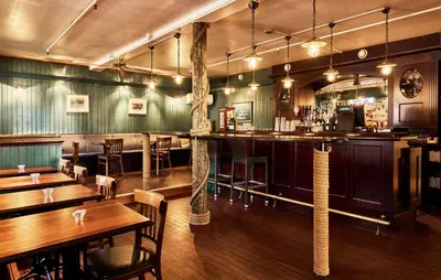 a bar in a restaurant with wooden tables and chairs at Bekkjarvik Gjestgiveri in Bekkjarvik