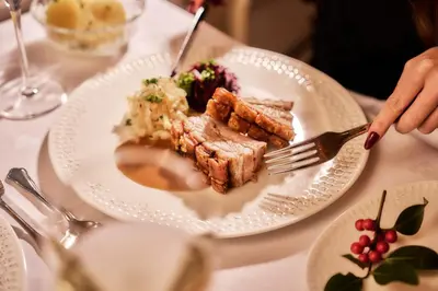 a plate of food on a table with a person holding a fork at Bekkjarvik Gjestgiveri in Bekkjarvik