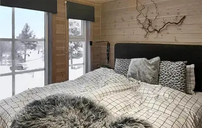 a bedroom with a bed with a blanket and windows at Awesome Home In Kvam With Sauna in Kvam