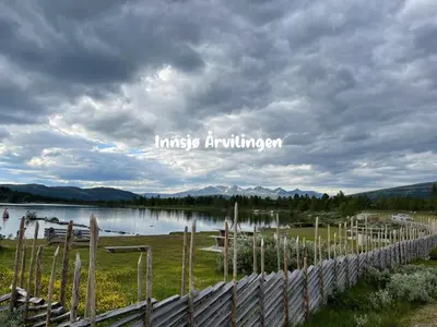 a fence in front of a lake with a cloudy sky at Maurtua - cabin in lovely surroundings in Kvam
