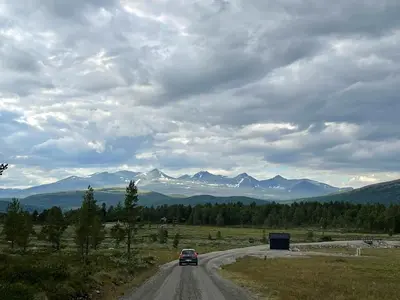 a car driving down a road with mountains in the background at Maurtua - cabin in lovely surroundings in Kvam