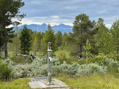 a cross in a field with mountains in the background at Maurtua - cabin in lovely surroundings in Kvam