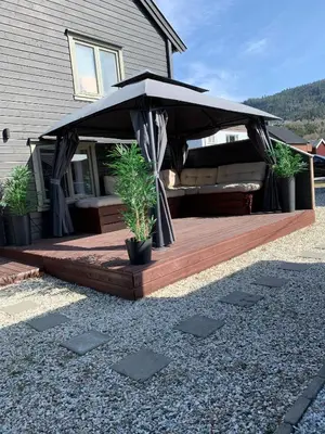 a wooden deck with an umbrella in front of a house at Private house in Orkanger, 35 minutes from Trondheim in Orkanger