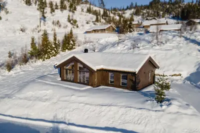 a log cabin in the snow with snow on the roof at Chill cabin - fantastic view and nice hiking area in Aurdal