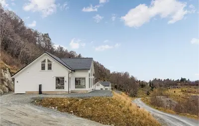 a white house on a hill with a dirt road at 4 Bedroom Amazing Home In Skånevik in Skånevik