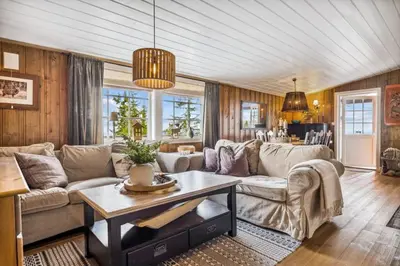 a living room with a couch and a table at Cozy and comfortable cabin in the center of Sjusjøen with a large terrace in Ringsaker
