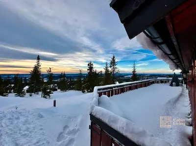 a snow covered yard next to a house with a fence at Cozy and comfortable cabin in the center of Sjusjøen with a large terrace in Ringsaker