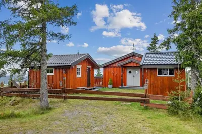 a home with a wooden fence and a house at Cozy and comfortable cabin in the center of Sjusjøen with a large terrace in Ringsaker