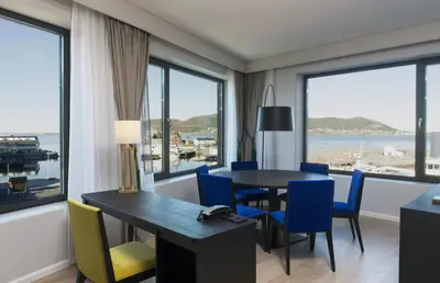 a dining room with a table and chairs and windows at Thon Hotel Fosnavåg in Fosnavåg