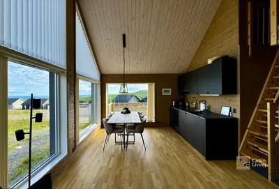 a kitchen and dining room with a table and some windows at Cozy cabin on Sjusjølia by the trail network sauna in Ringsaker