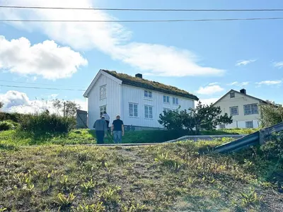 two people standing in front of a white house at 7 person holiday home in Averøy-By Traum in Averoy