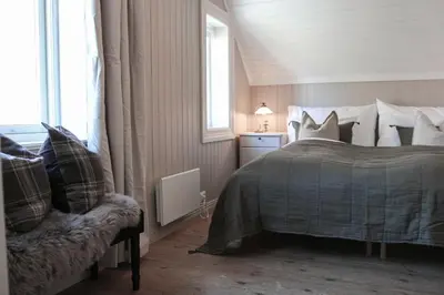 a bedroom with a bed and a chair and a window at Petrines Gjestgiveri in Norddal